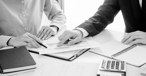 A team reviewing billing statements and reports together at a desk with a calculator.